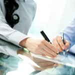 Tilt up of two business partners signing a contract and closing the deal